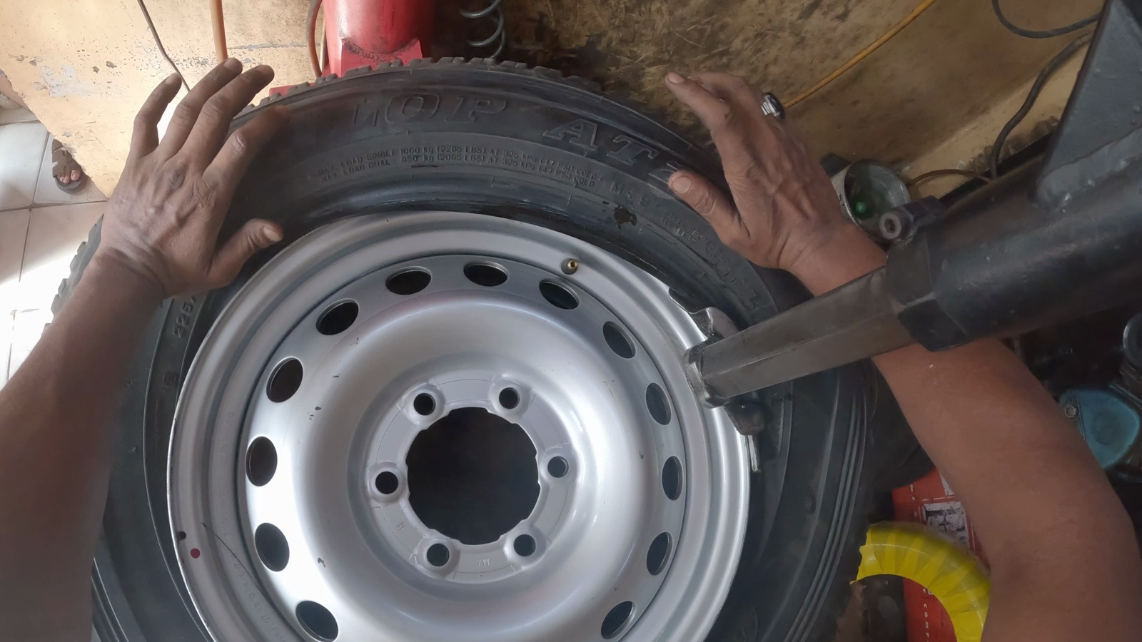 Hands fitting a tire onto a rim at a tire machine