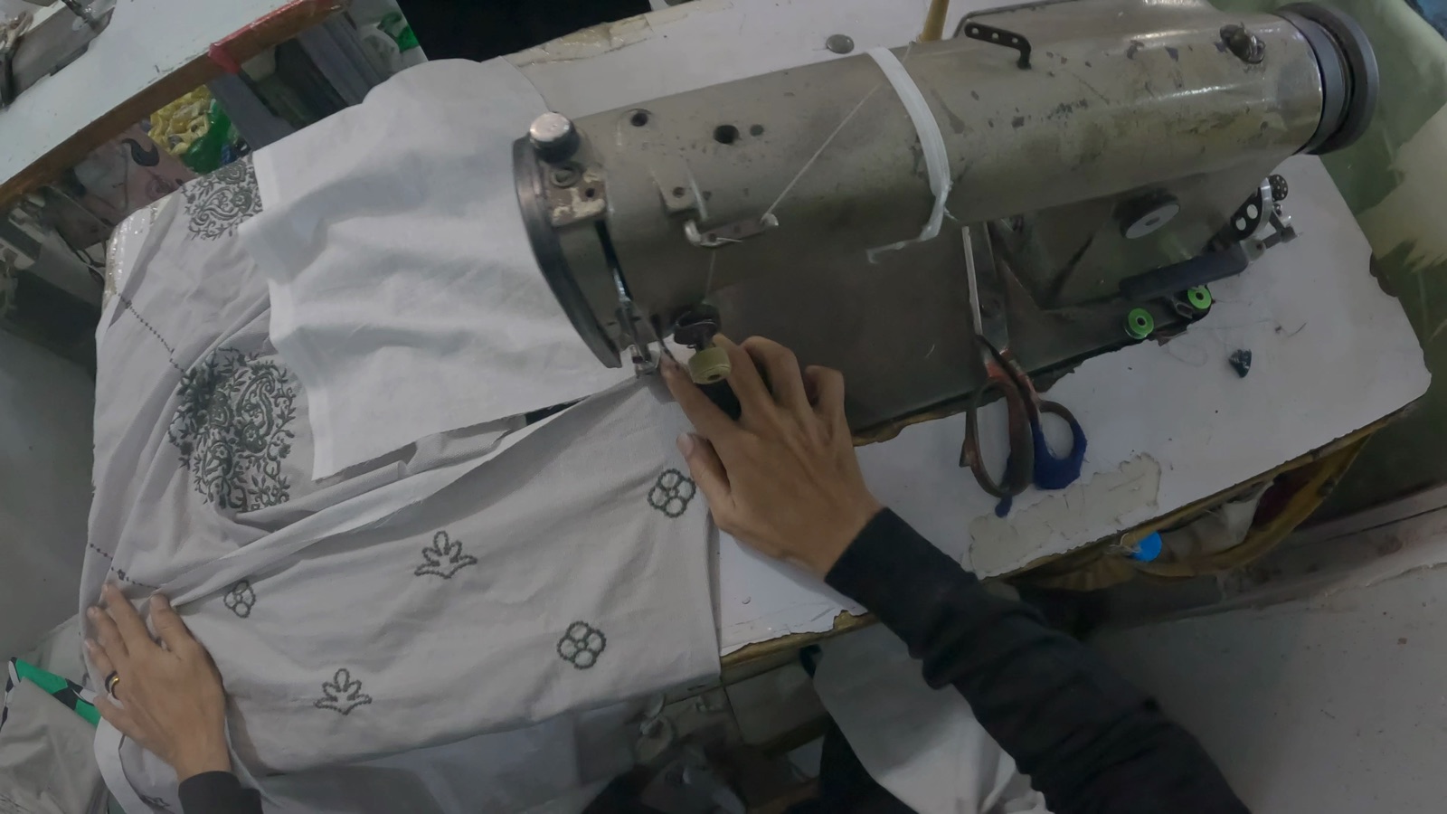 A worker guiding patterned fabric through an industrial sewing machine